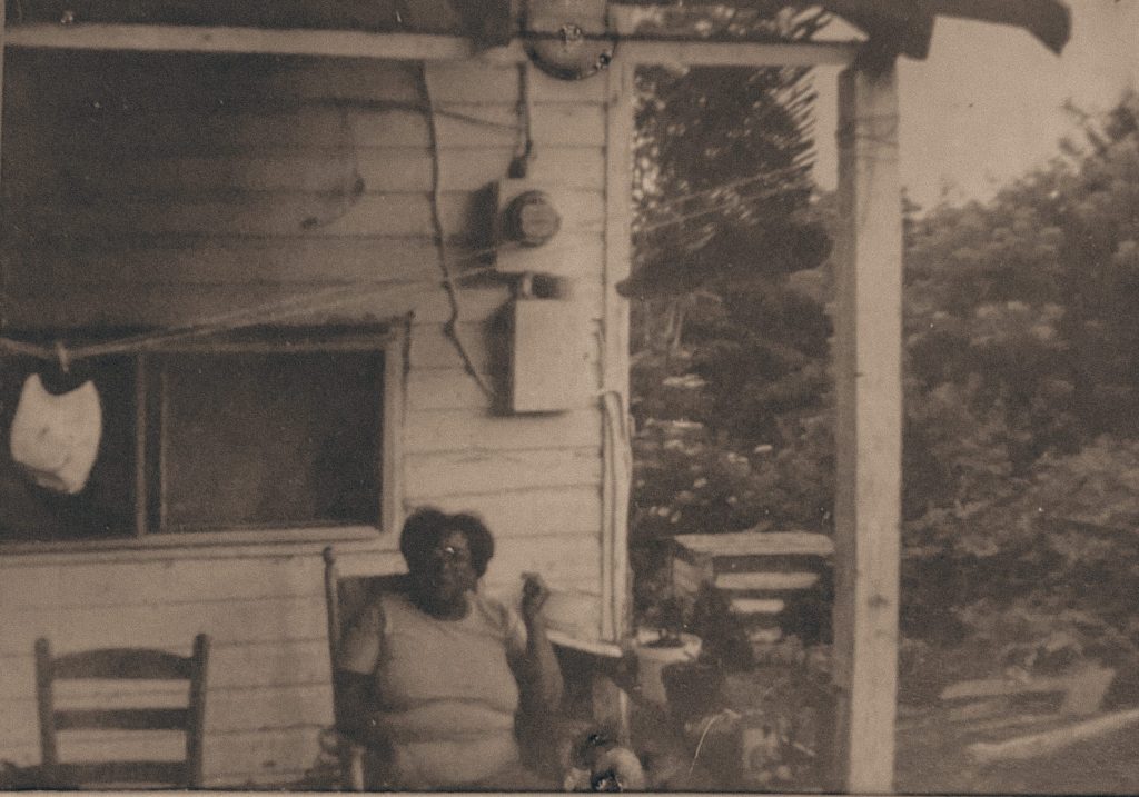 Black woman sitting on porch on a rocking chair outside of home