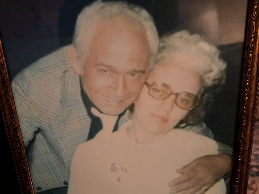 a man hugging a woman from behind  posing for a photo