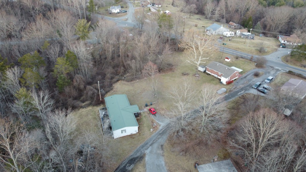 Aerial photograph of several homes adjacent to a main road roads that lead to the homes with several cars parked outside
