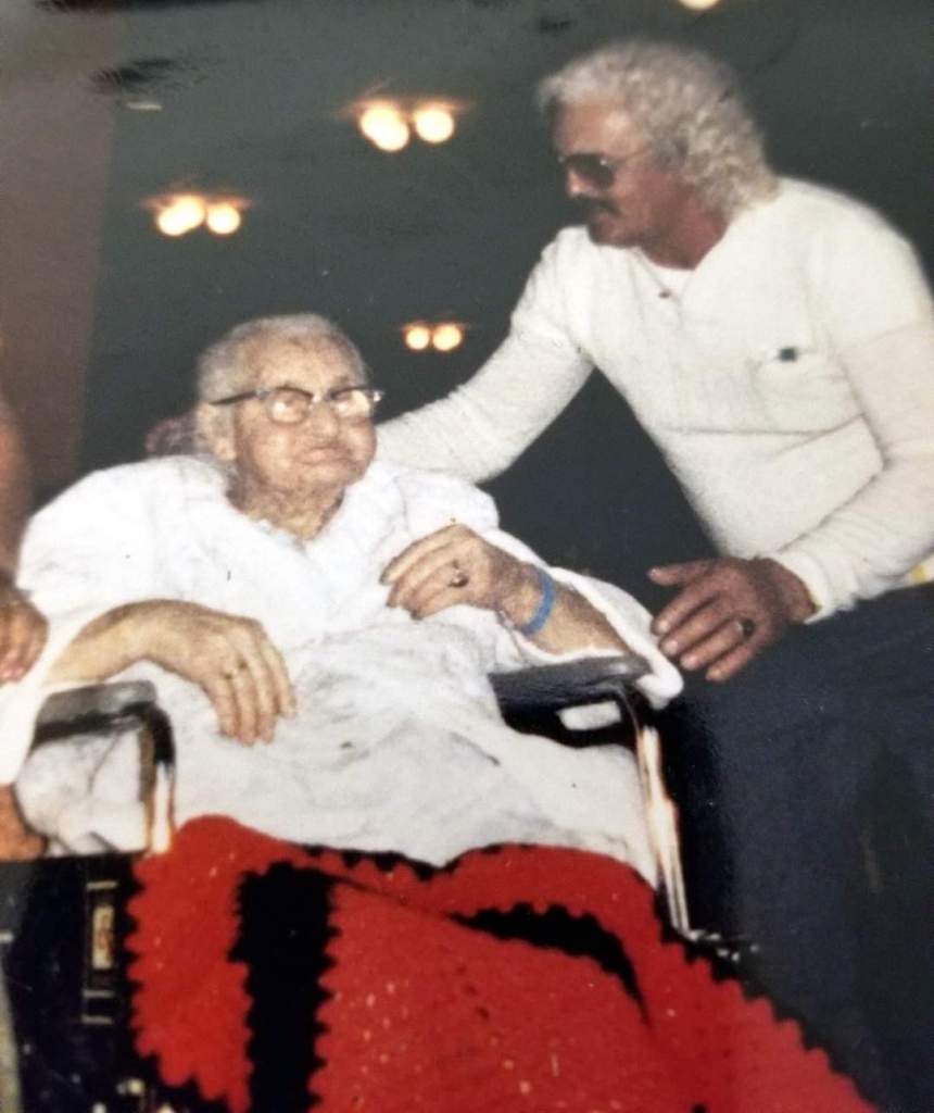 an elderly man wheeling an elderly woman's wheelchair