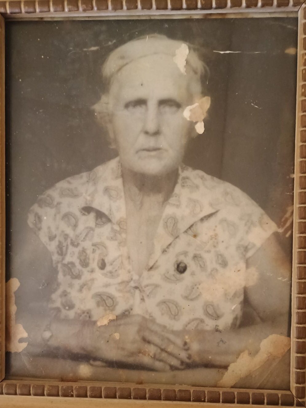 old and weathered photo of an elderly lady sitting posing for a photo