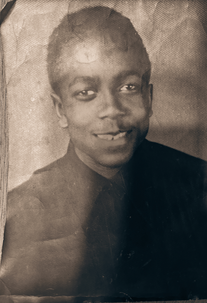 Black and white photograph of a young man seated smiling for a portrait