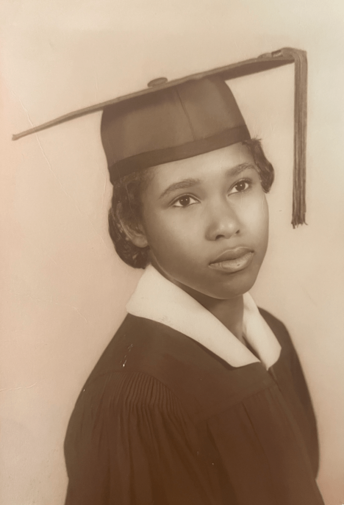 Black and white portrait of a young woman looking to the distance wearing a graduation cap and gown