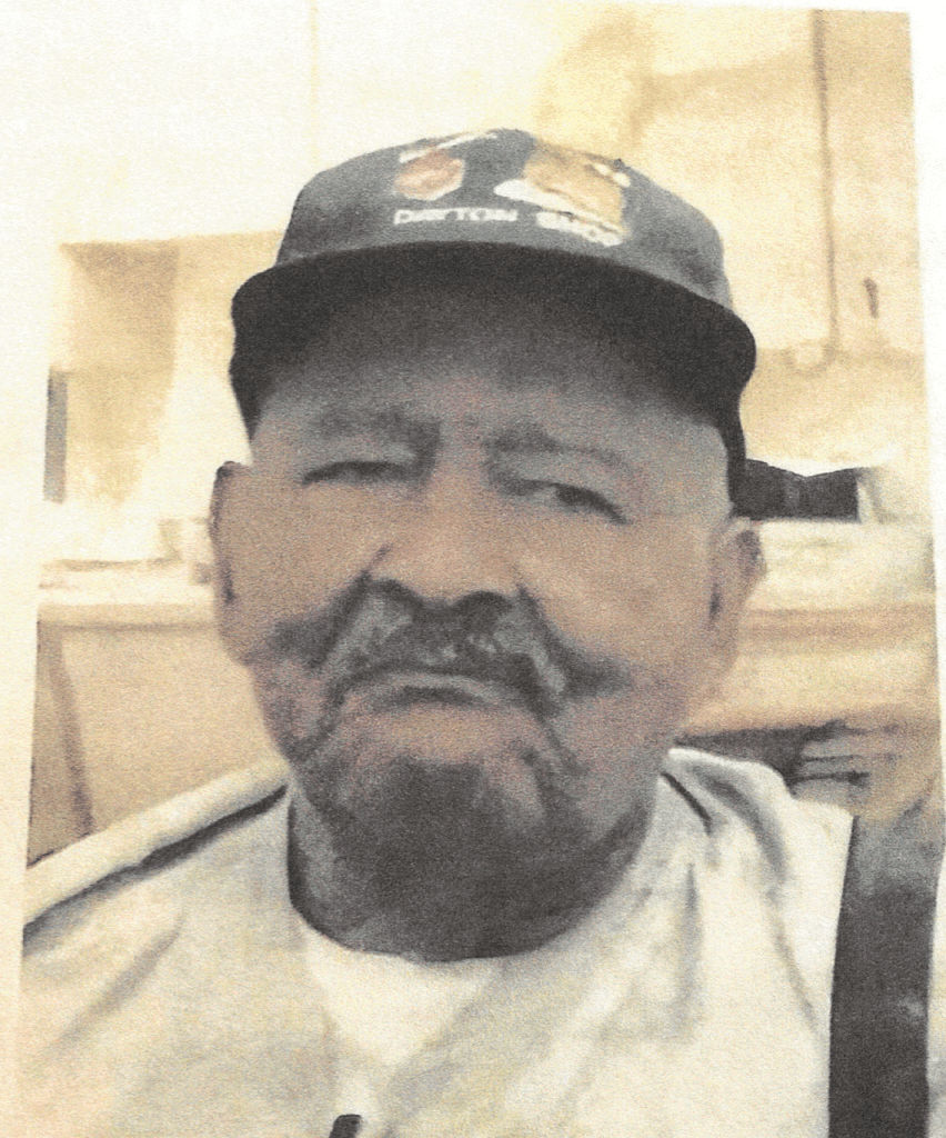 Older man wearing a baseball cap sitting for a photo