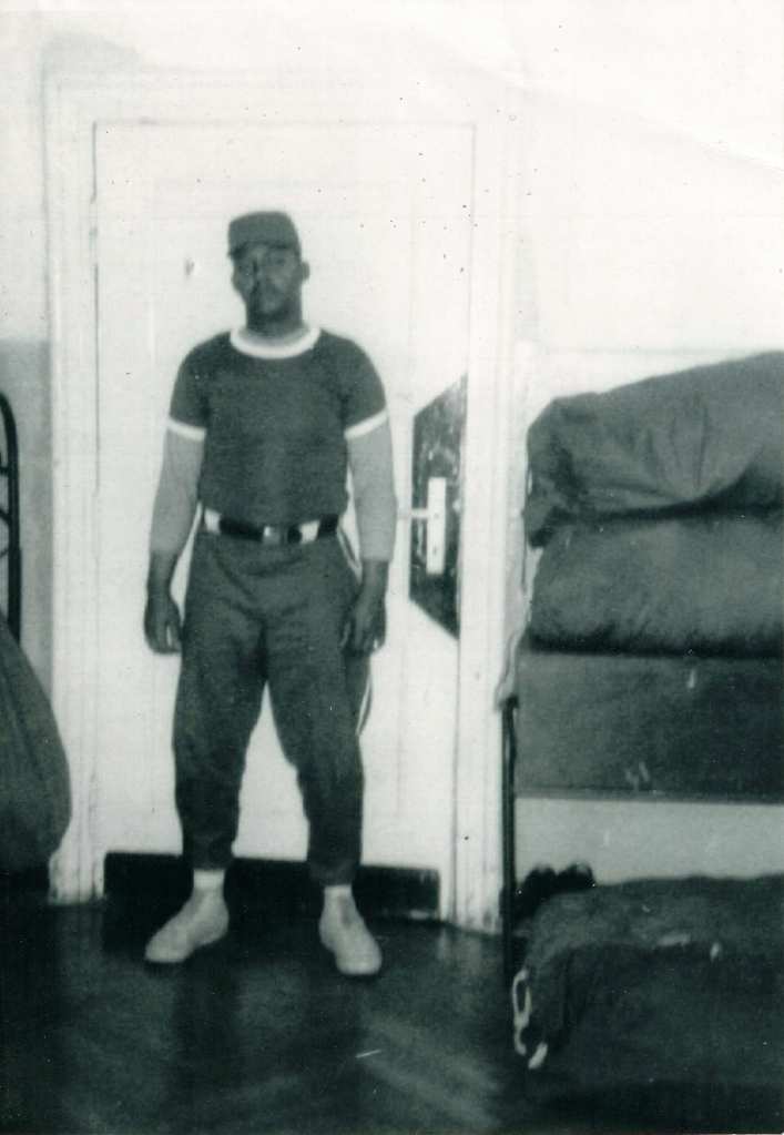 Old photo of Richard Smith in a t-shirt, belted pants, and a cap.