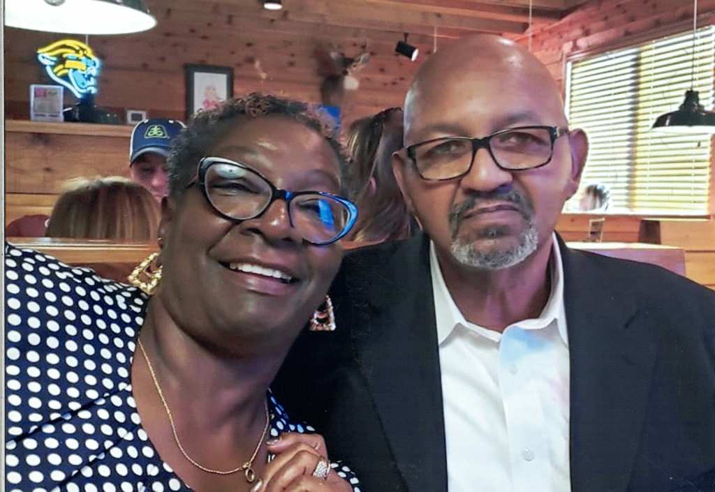 Photo of couple in a restaurant booth. Woman is leaning in towards husband.