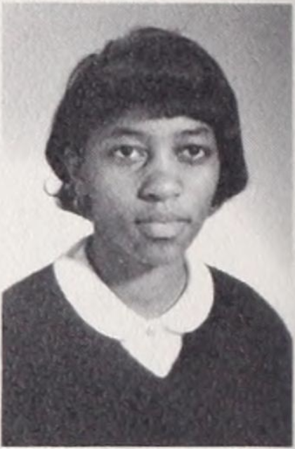 Black and white yearbook photo of a young girl wearing a sweater with a collared shirt underneath with a soft expression.