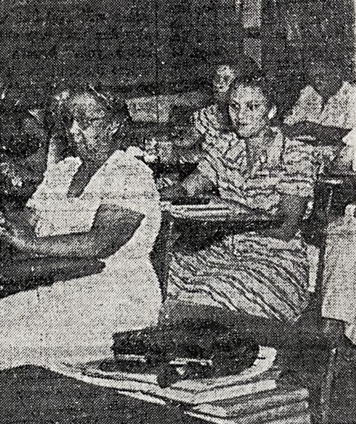 Black and White photo of teachers sitting in desks in a classroom 