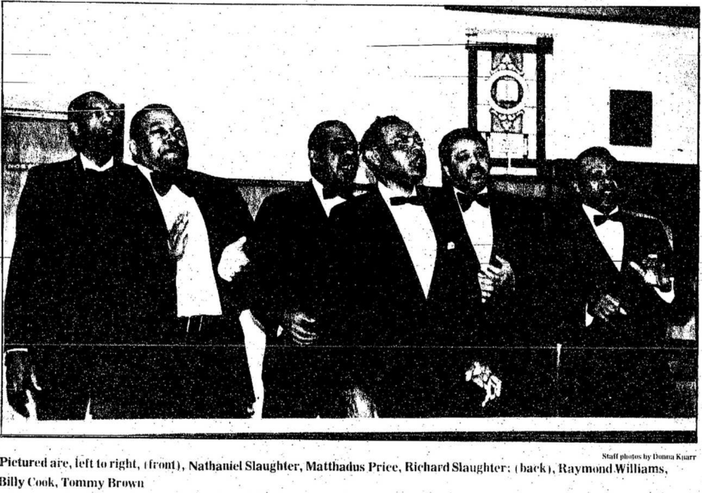 Black and white newspaper clipping of a candid picture of six men wearing suits and bowties singing. The caption of the clipping reads "pictured are, left to right, (front), Nathaniel Slaughter, Matthadus Price, Richard Slaughter: (back), Raymond Williams, Billy Cook, Tommy Brown."