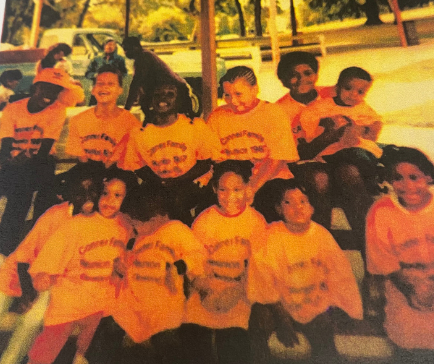 Image of a dozen children in matching shirts posing under a park 